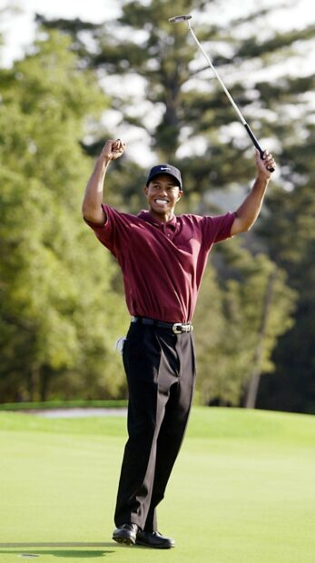 Tiger Woods celebrating a golf victory on the green wearing a red shirt and black pants