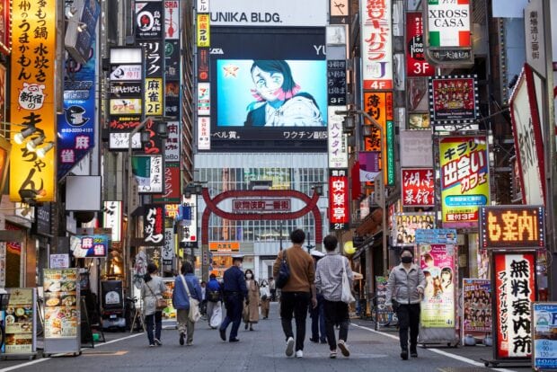 People walking in the busy Tokyo Japan street with colorful signs and buildings