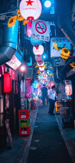 Narrow Tokyo alley with lanterns and people walking during night in Japan