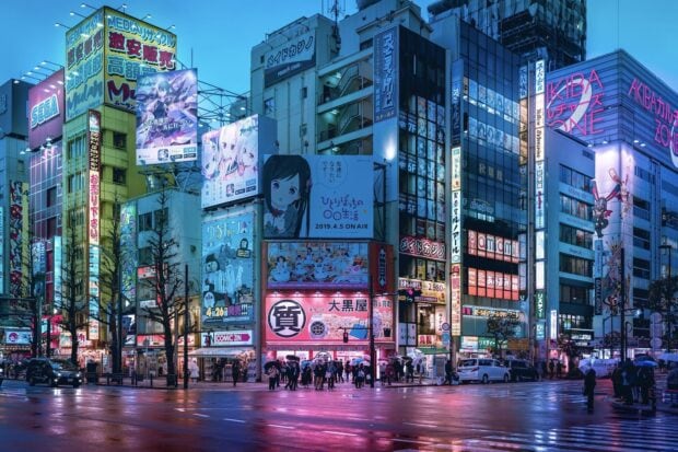Tokyo city street with anime billboards and neon lights reflecting on wet pavement in Japan
