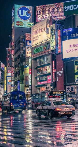 Tokyo city street with colorful signs and vehicles on rainy night in Japan