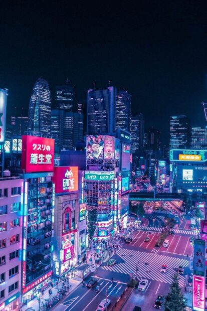 Neon lights illuminate busy Tokyo Japan streets at night with crowds and traffic