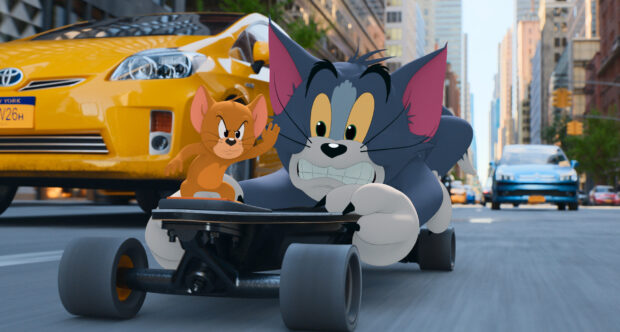 Tom and Jerry characters riding a skateboard through the city street in a playful chase