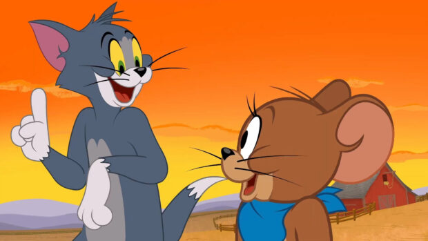 Tom and Jerry cartoon characters smiling in a rural setting with an orange sunset sky