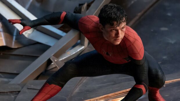 Tom Holland in a Spider Man suit crouching in an action pose on a metal surface
