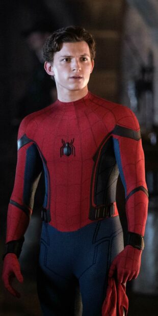 Tom Holland wearing a Spider Man suit standing with a serious expression