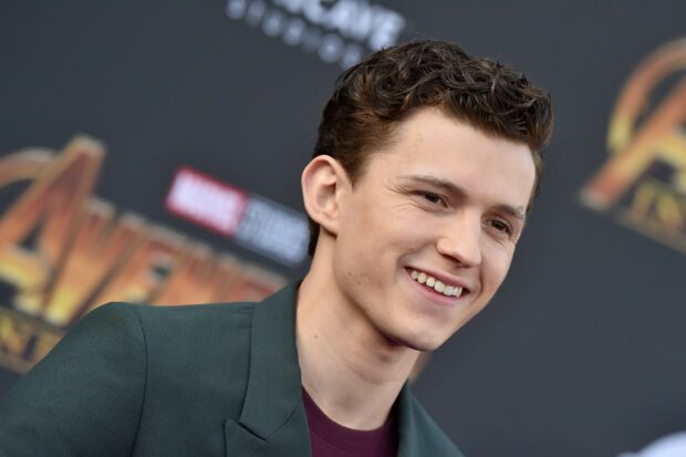 Tom Holland smiling at the Avengers premiere event with a dark green jacket