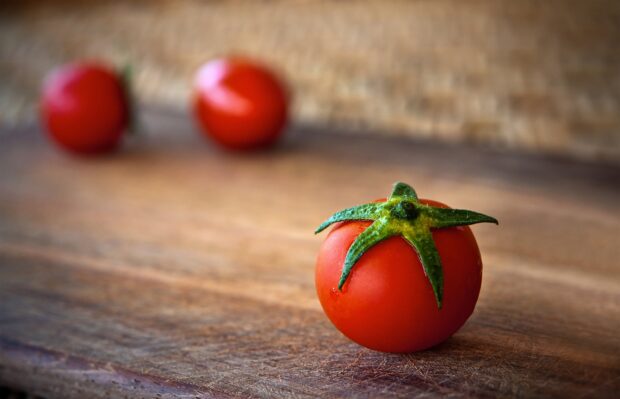 A close up of a fresh tomato on a wooden surface showing natural texture