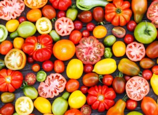Various colorful heirloom tomato varieties spread on a wooden surface showing their unique shapes and colors