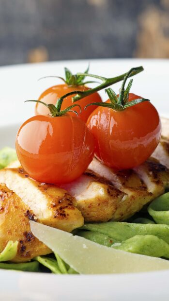 Fresh tomato on grilled chicken served with green pasta