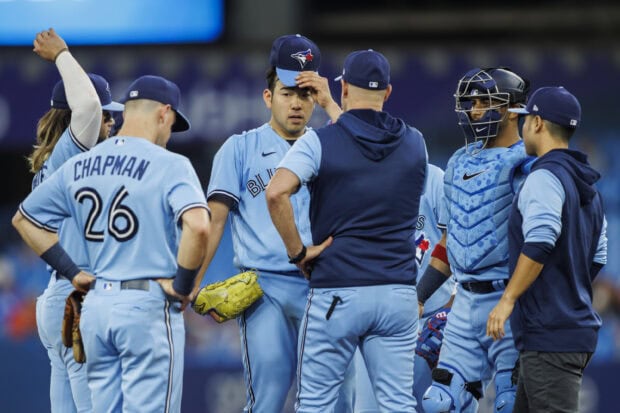 Toronto Blue Jays player discussing game strategy with teammates on the field