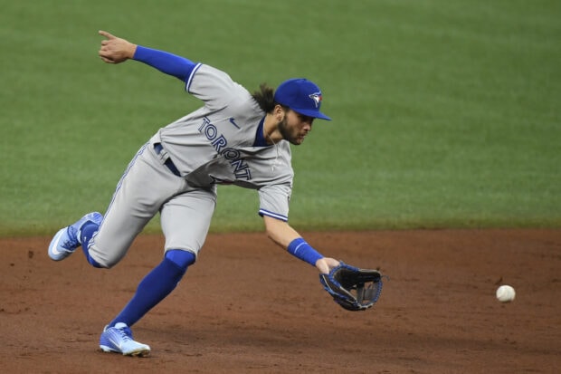 Toronto Blue Jays player stretching to catch a baseball on the field