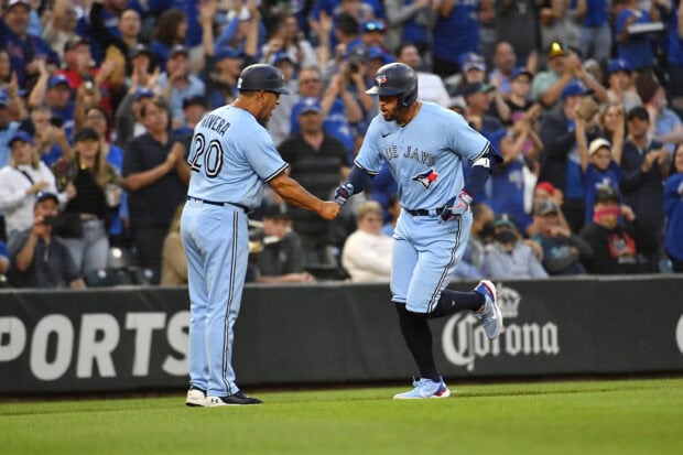 Two Toronto Blue Jays players celebrating during a baseball game in front of cheering crowd