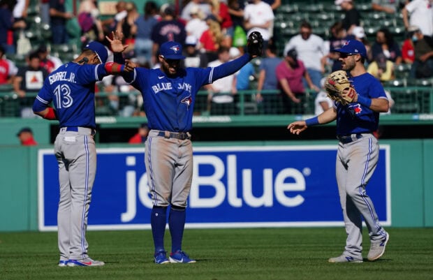 Three Toronto Blue Jays players celebrating on the baseball field during a game