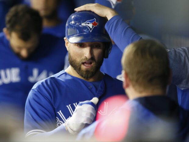 Toronto Blue Jays player wearing helmet and celebrating in dugout with teammates