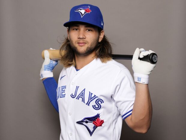 A Toronto Blue Jays player posing with a baseball bat over his shoulders in a white uniform