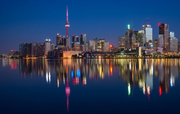 Toronto skyline at night with colorful lights reflecting on calm water