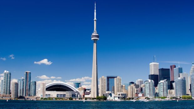 Toronto skyline features the CN Tower and surrounding buildings on a clear sunny day