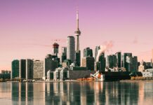 Toronto skyline with CN Tower reflecting on calm water under a pink sky