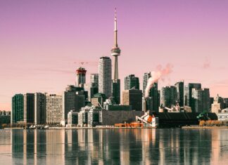 Toronto skyline with CN Tower reflecting on calm water under a pink sky