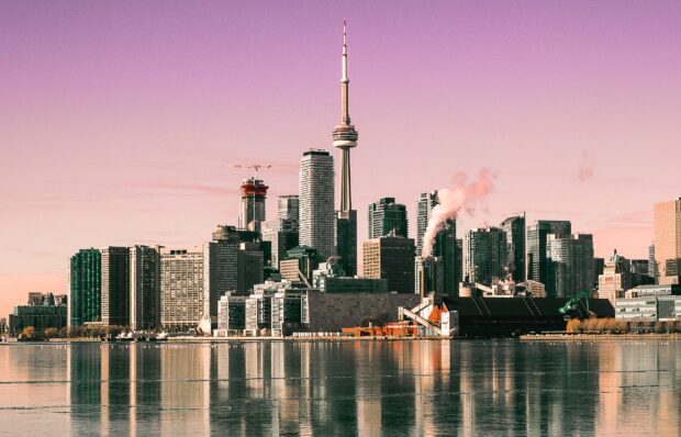 Toronto skyline with CN Tower reflecting on calm water under a pink sky