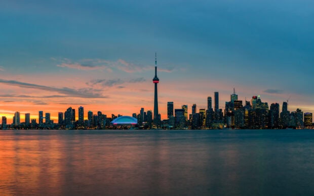 Toronto skyline with the iconic CN Tower at sunset over calm water