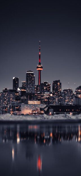 Toronto skyline illuminated at night reflecting on calm water surface