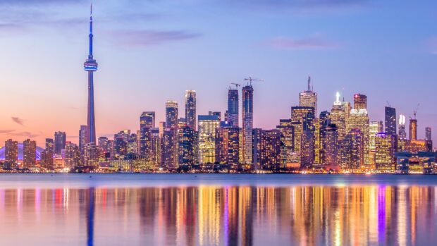 Toronto skyline at dusk with colorful reflections on the water and illuminated buildings