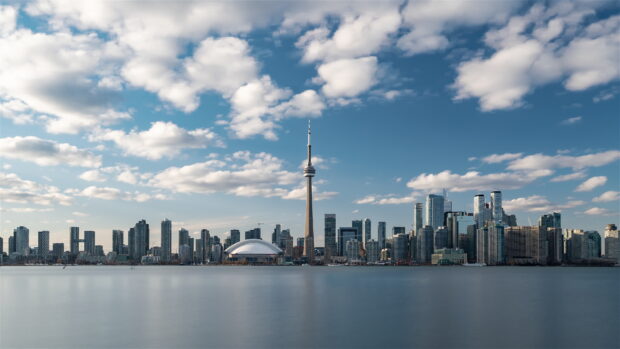 Toronto skyline with the CN Tower and city buildings under a cloudy blue sky
