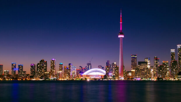 Toronto skyline at night with illuminated buildings and a clear sky viewed from across the water