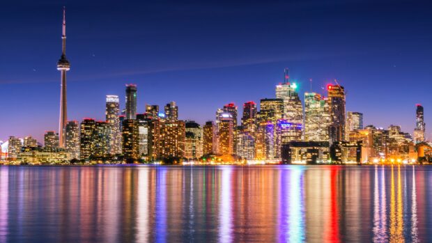 Toronto skyline at night with vibrant city lights reflecting on the water