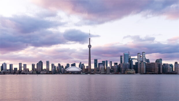 Toronto skyline seen from across the water under a cloudy sky at sunset