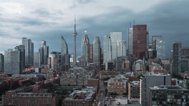 Toronto skyline view with iconic CN tower and modern high rise buildings in a cloudy sky