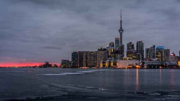 Toronto skyline with illuminated buildings along the frozen lake at sunset
