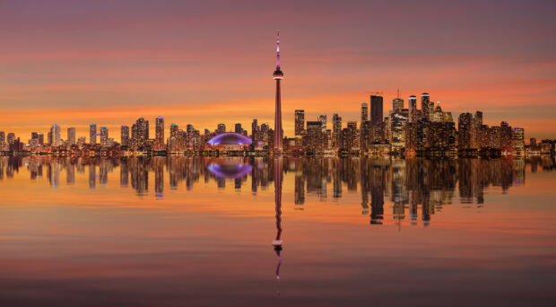 Toronto skyline with calm water reflection at sunset showcasing city lights and buildings