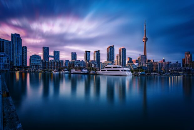 Toronto skyline with modern skyscrapers and boats on calm water at dusk