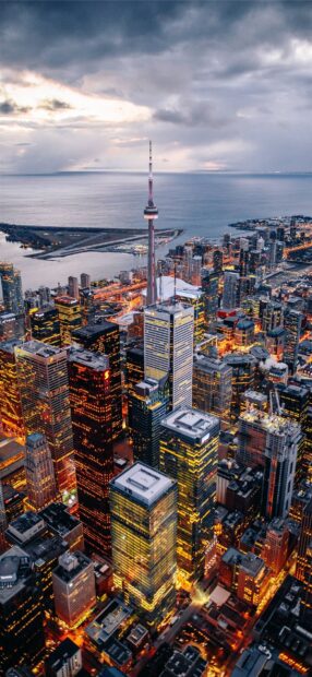 Toronto skyline seen at dusk with illuminated buildings and Lake Ontario in the background