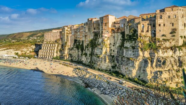 Historic cliffs and buildings in Tropea with a sandy beach and clear sea waters