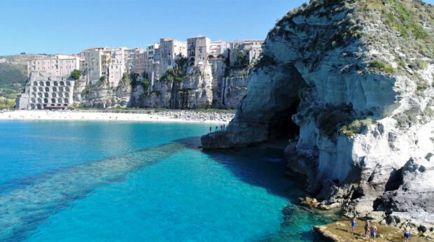Tropea town cliffs and cave with clear turquoise sea on a sunny day