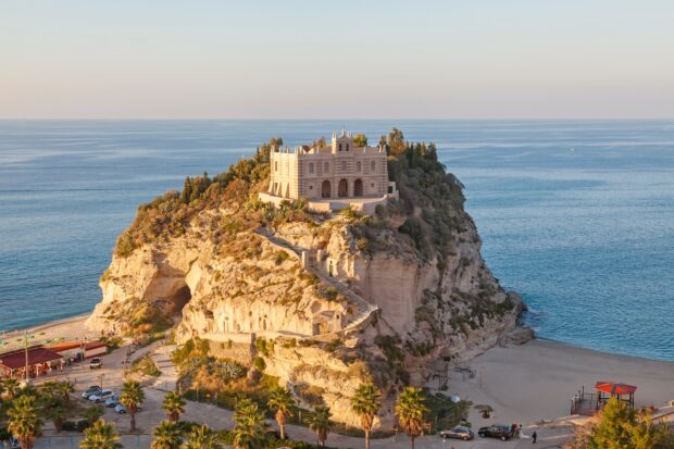 A historic building on a rocky cliff overlooking the sea in Tropea