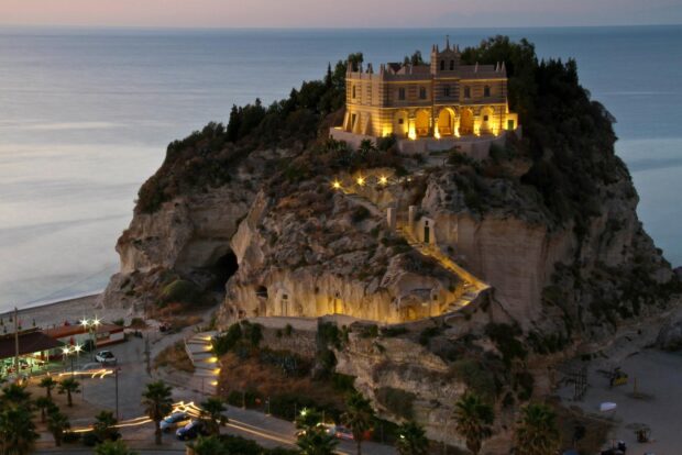 Historic Tropea cliffside castle illuminated at night with sea view