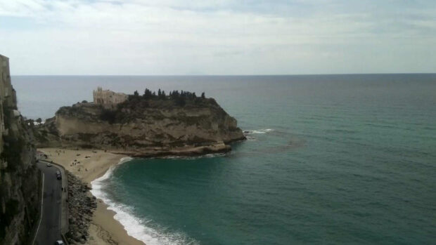 Tropea coastal cliff with historic building and turquoise sea under cloudy sky