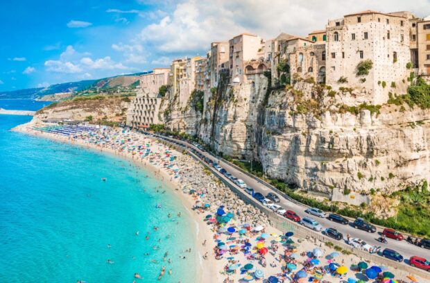 Tropea town cliff and beach with turquoise water and colorful umbrellas on a sunny day