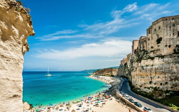 Turquoise sea and cliffs of Tropea with beachgoers enjoying summer sunshine