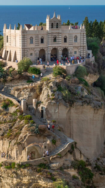 Historic Tropea cliffside castle with visitors enjoying the coastal views in Tropea