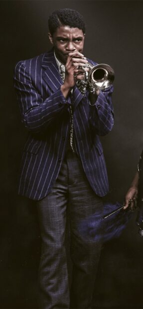 A man playing trumpet wearing a striped suit jacket and plaid pants