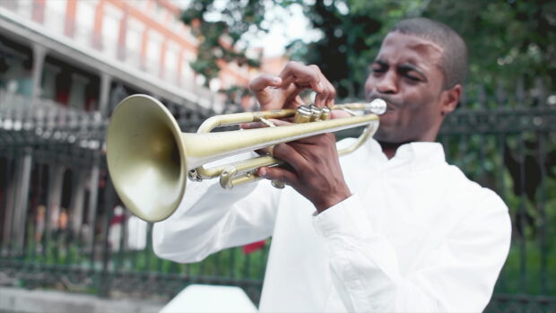 Man playing trumpet passionately outdoors with trumpet