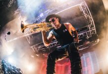 Male musician playing trumpet on stage with lighting and smoke effects