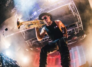 Male musician playing trumpet on stage with lighting and smoke effects