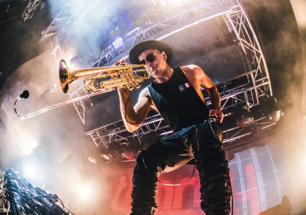 Male musician playing trumpet on stage with lighting and smoke effects
